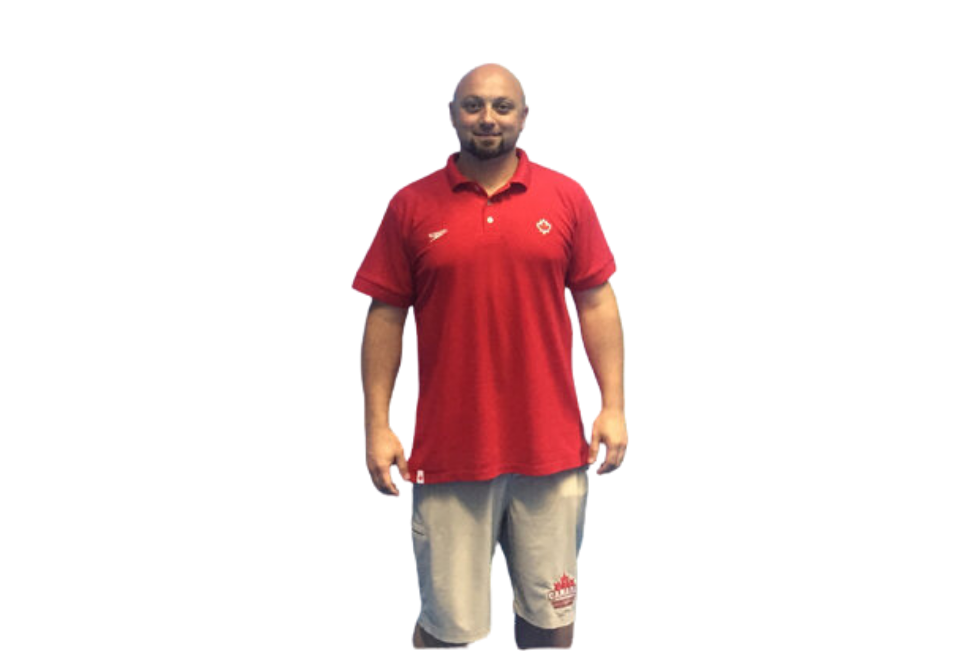 A male osteopath in a red Team Canada polo shirt and beige shorts stands tall with relaxed shoulders and balanced posture. His athletic stance and confident presence reflect a background in sports performance and manual therapy.